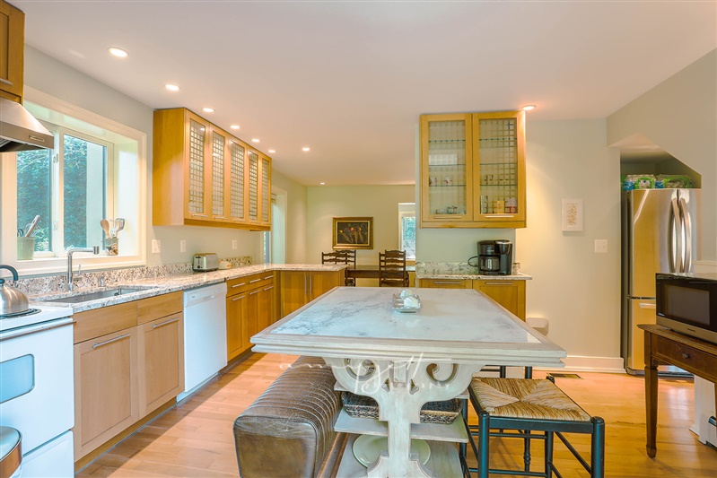 Renovated open kitchen with marble island and glass-front cabinetry
